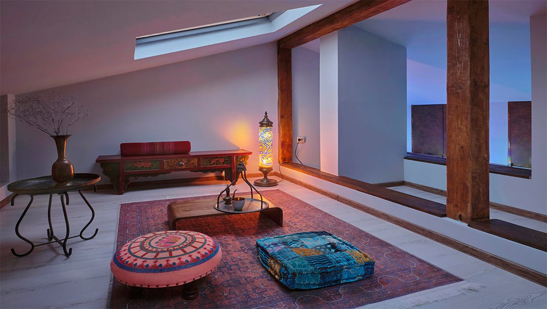 Cozy loft space with colorful floor cushions, a vintage bench, and a decorative lamp