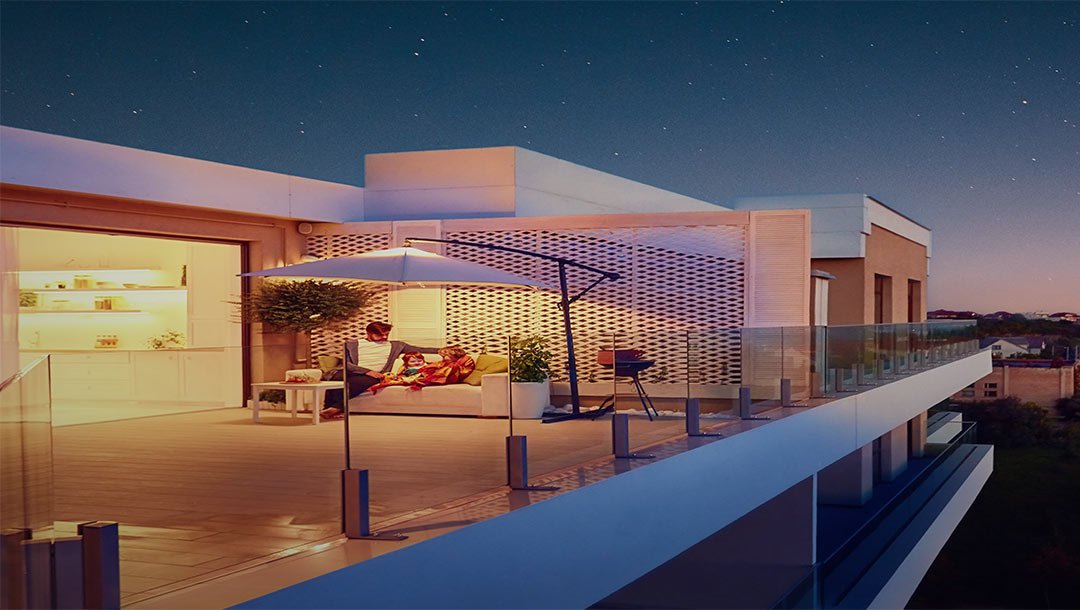 Family sitting on balcony of modern home at sunset