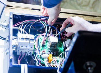 Hands working on electrical wiring inside a control panel