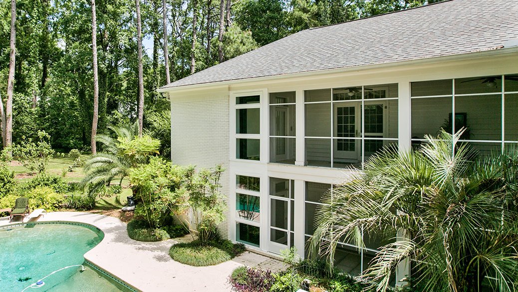 Two-story home with large screened windows overlooking a pool