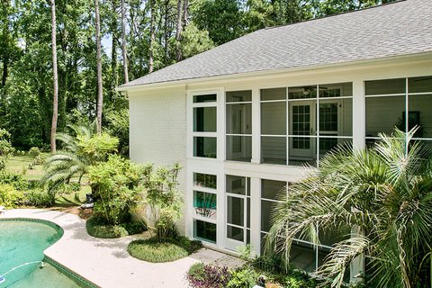 Two-story home with large screened windows overlooking a pool
