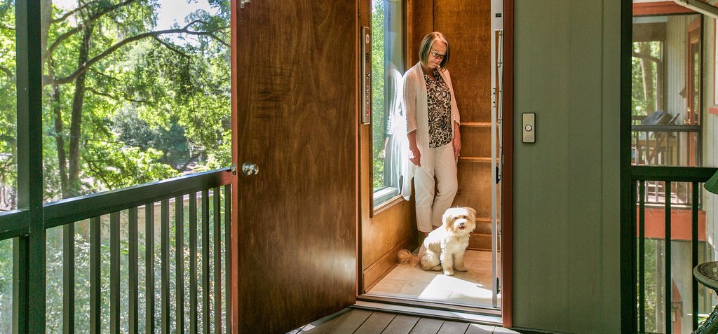 Woman and small dog standing inside a home elevator with the door open