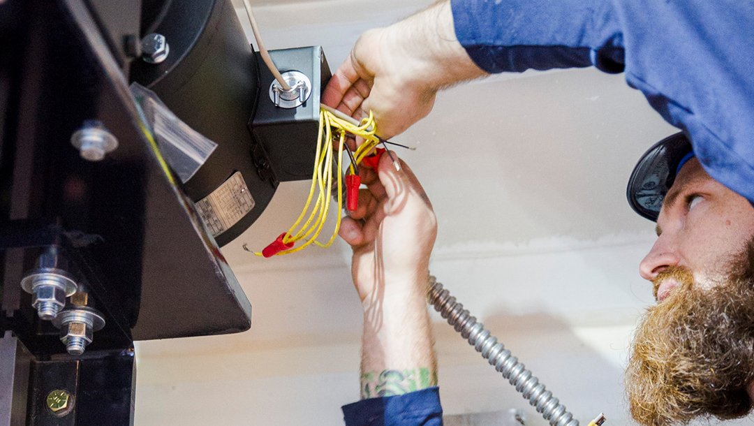 Technician working on electrical wires inside elevator machinery