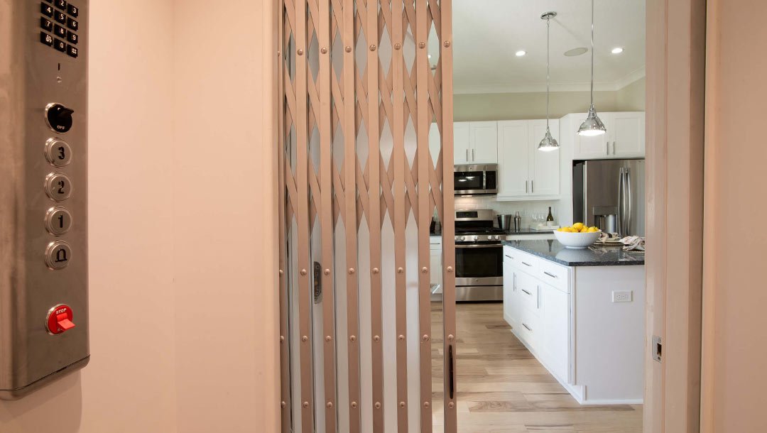 Open elevator gate facing a modern white kitchen