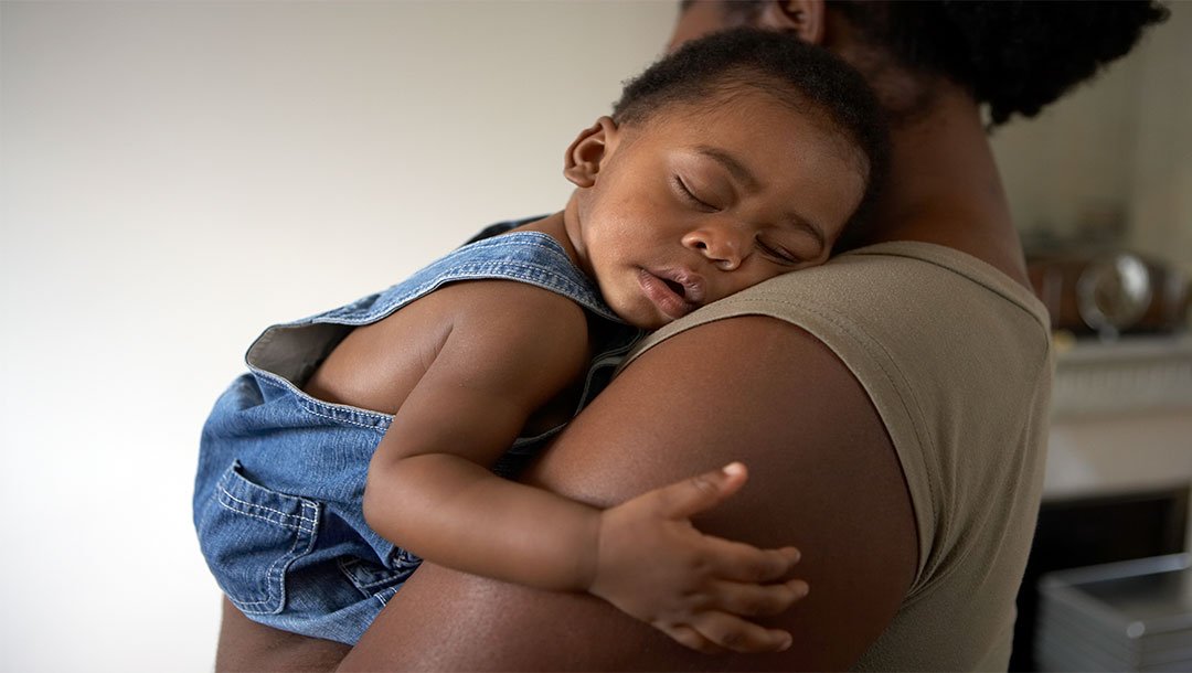 Sleeping toddler resting on an adult’s shoulder