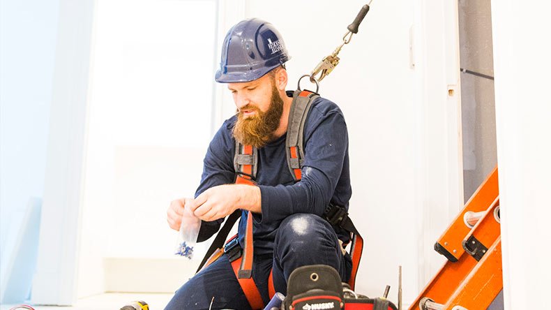 Repairman wearing a harness holding a small bag